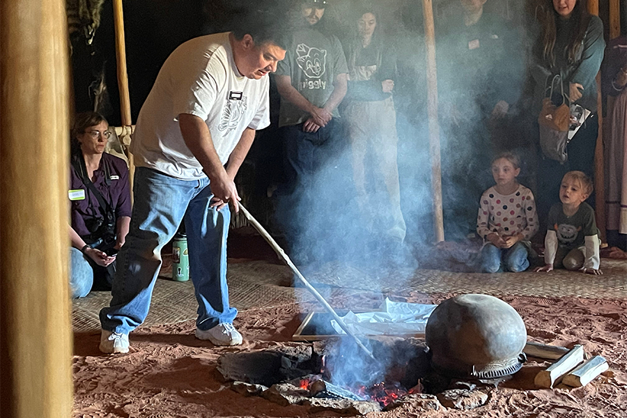 Man tends a pit cooking fire